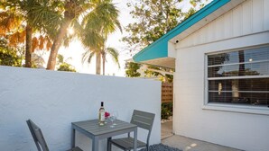 A patio with a table and chairs, a bottle of wine, and a glass. - Barefoot Mermaid 4, steps to the beach (Anna Maria)