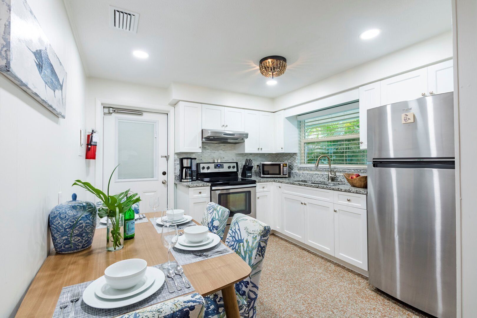 A modern kitchen with white cabinets, stainless steel appliances, and a dining area set for four.