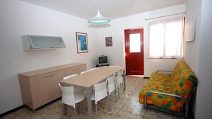 Un espace de vie compact comprenant une table à manger, des chaises, un canapé, un téléviseur et un meuble.