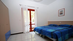 Une chambre à coucher avec un lit, une porte avec des rideaux, un tableau encadré au mur et une armoire.
