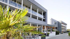 Un edificio moderno con varios balcones, mobiliario exterior y plantas en macetas.
