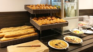 Un bufé con pan, pasteles y una tabla de cortar con un cuchillo.