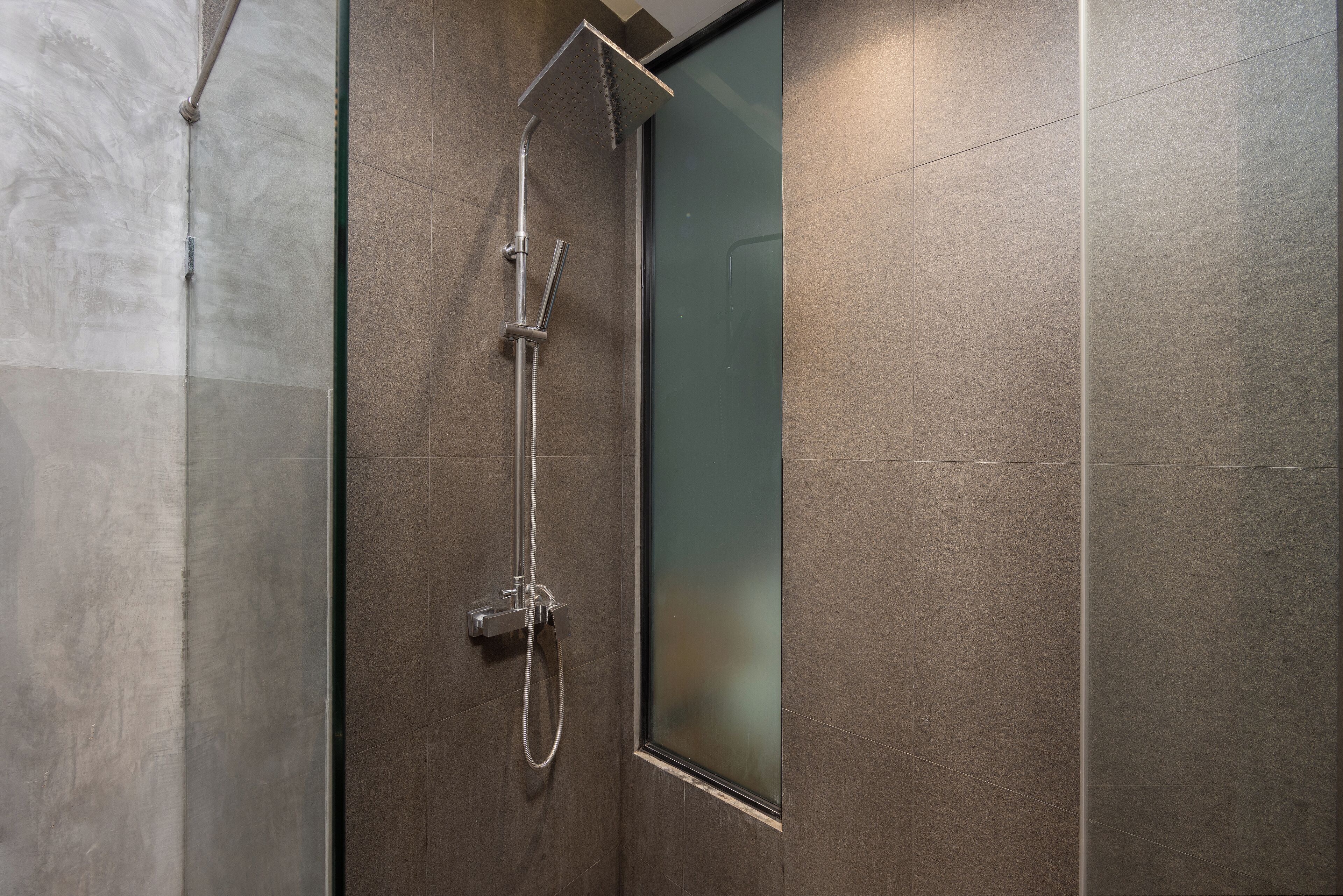 A modern shower with a glass door, a handheld showerhead, and a wall-mounted control panel.