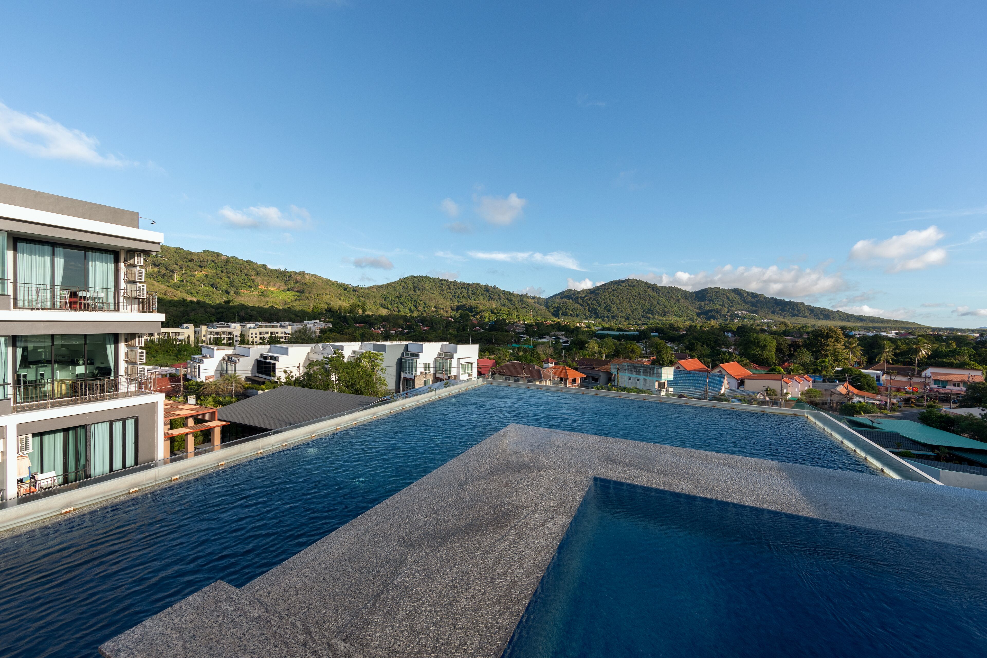 A swimming pool with a view of a modern building and surrounding hills.