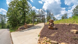 A paved pathway leading to a gazebo in a landscaped area with rocks and mulch.