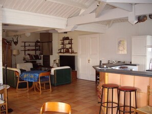Un vaste espace de vie comprenant un coin repas avec une table et des chaises, ainsi qu’une cuisine dotée d’un comptoir-bar.