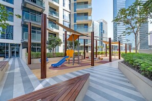 Relax in the adjacent outdoor space with a children's play area featuring a slide and swing set, surrounded by a bench and walkway.
