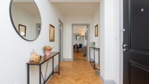 A hallway with a wooden herringbone floor, a round mirror, and a black door. - Stunning 2 bed retreat in the heart of Bath - Pass the Keys (Bath)