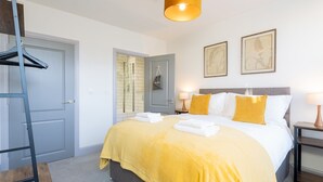 A hotel room with a bed, a bedside table with lamps, a wardrobe, and a shower area. - Stunning 2 bed retreat in the heart of Bath - Pass the Keys (Bath)