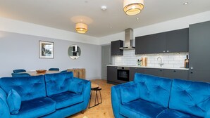 A modern living room with two blue sofas, a wooden coffee table, and a yellow rug. - Stunning 2 bed retreat in the heart of Bath - Pass the Keys (Bath)