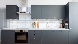 A modern kitchen with grey cabinets, a white countertop, a built-in oven, and a stainless steel range hood. - Stunning 2 bed retreat in the heart of Bath - Pass the Keys (Bath)