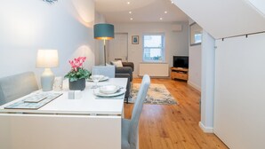 Ein modernes Wohnzimmer mit Essbereich, Holzboden, einem Fernseher und einer Treppe zu einer oberen Ebene.