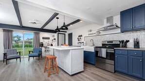 Una cocina moderna con armarios azules, una isla central y un comedor con dos sillas.