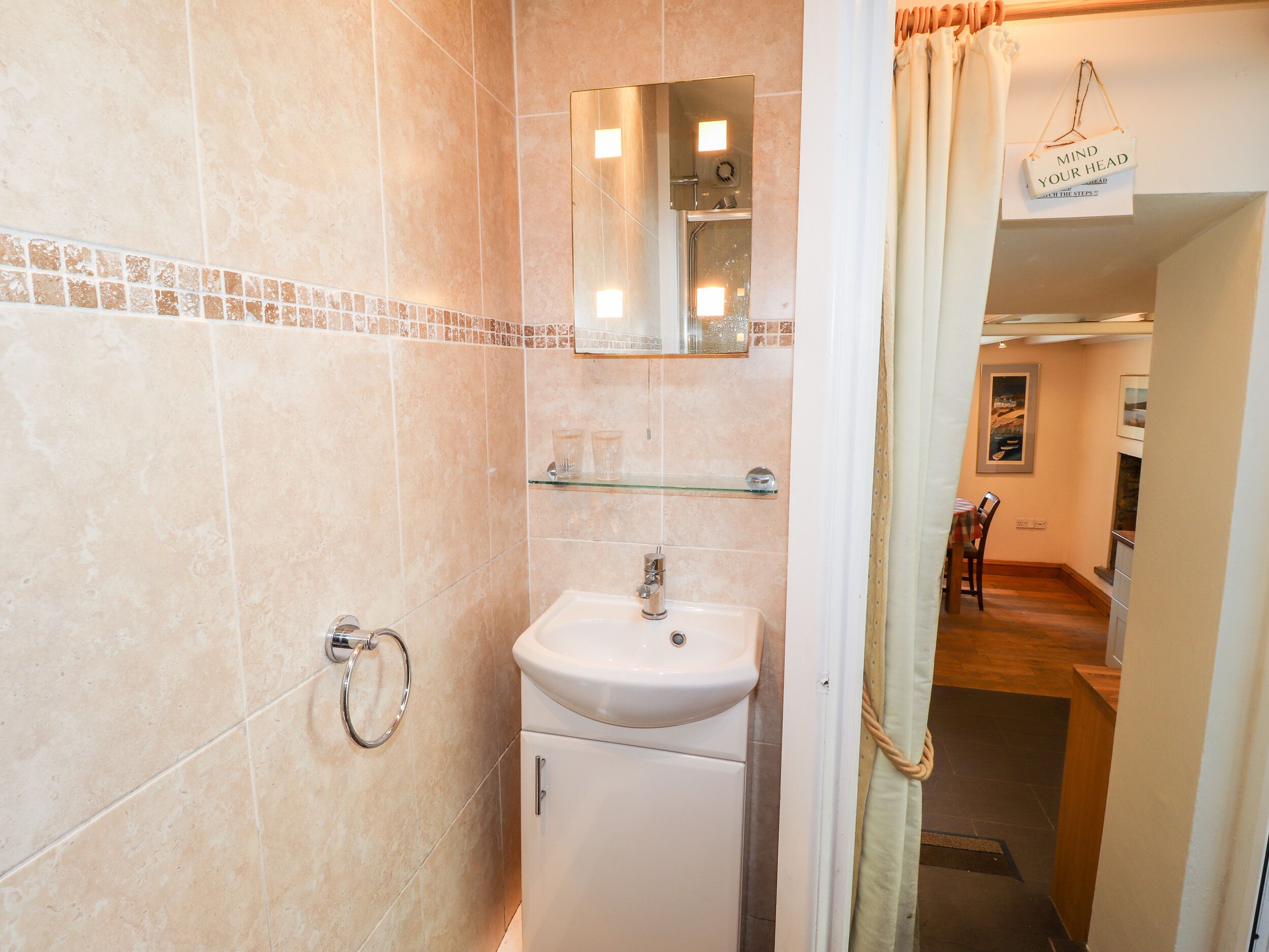 Un baño con lavabo, espejo y toallero.