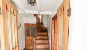 A wooden staircase with a handrail, leading to a door with frosted glass panels.