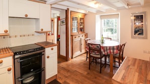 A kitchen with wooden cabinets, a stove, and a dining area with a table and chairs.