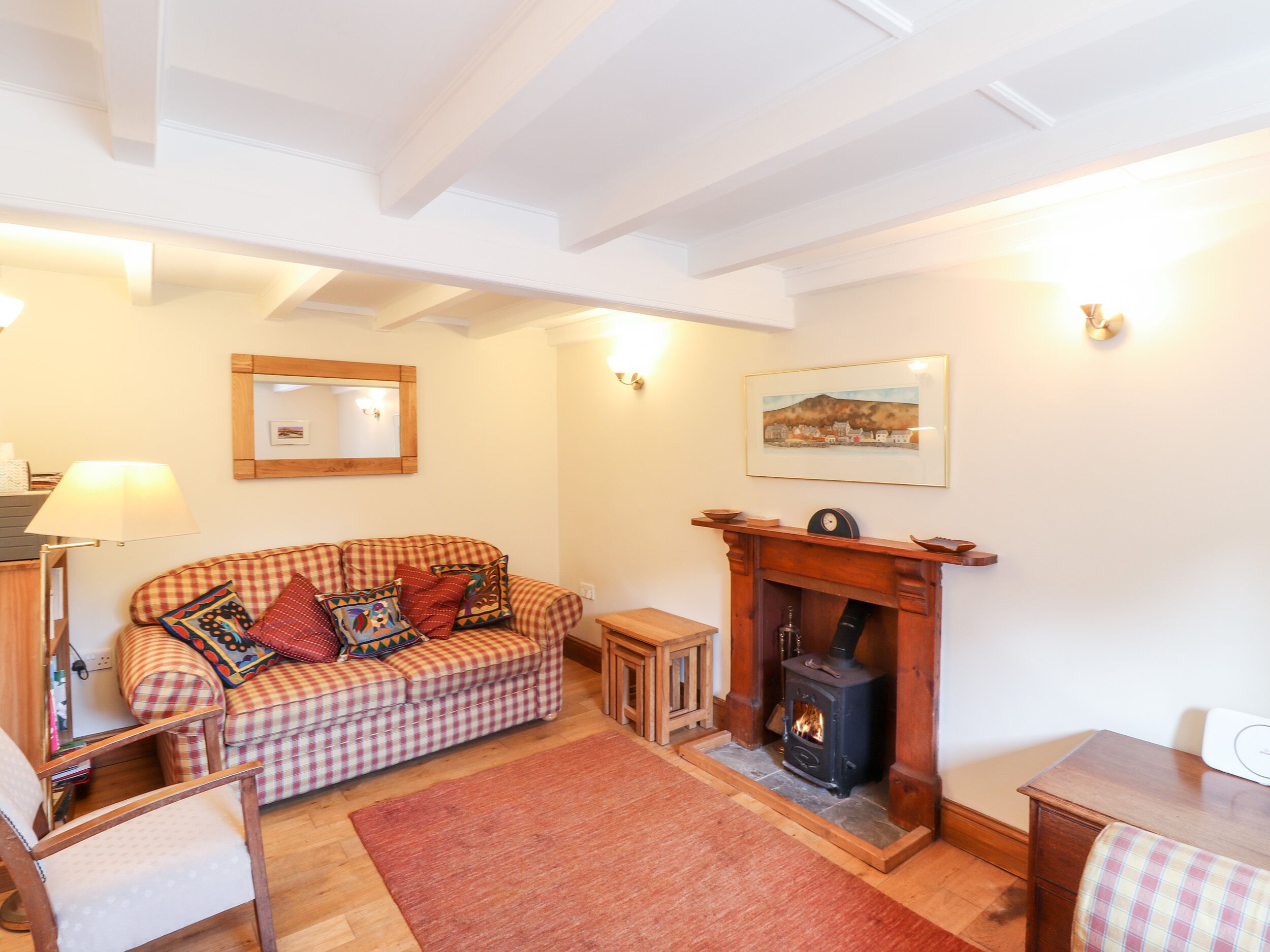 A cozy living room with a checkered sofa, a fireplace, a mirror, and a painting on the wall.