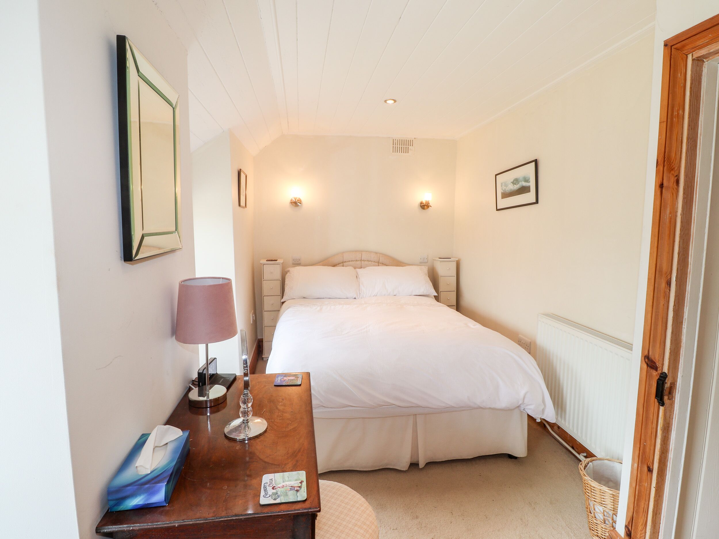 Ein Schlafzimmer mit Bett, Nachttisch, Lampe und einem Bild an der Wand.