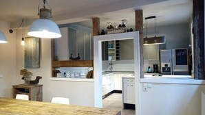 A modern kitchen with white cabinetry, a wooden dining table, and pendant lighting. - SEVORAGE (Walzbachtal)