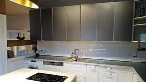 A modern kitchen with white cabinets, a built-in oven, and a stainless steel countertop. - SEVORAGE (Walzbachtal)