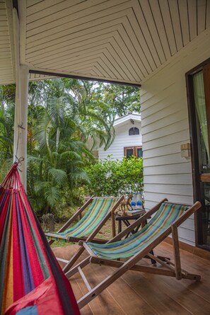 A covered outdoor area with two striped lounge chairs and a hammock.
