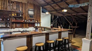Un coin bar rustique avec des tabourets en bois, un comptoir et des étagères remplies de bouteilles.