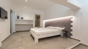 A modern bedroom with a large bed, a built-in bench, a TV, and a shower area.