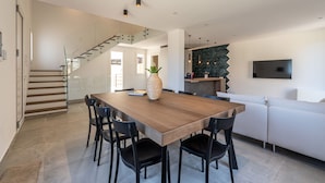 A modern kitchen with a wooden dining table, black chairs, a large vase, and a staircase leading to another level.