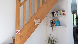 Eine Holztreppe mit Rauchverbot, einer weißen Wand und einem Bücherregal mit Büchern.