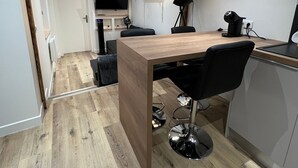 A modern kitchen with a wooden table, black chairs, and a large wall clock.