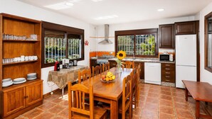 Una cocina con una mesa de comedor, sillas, un refrigerador, un microondas y una ventana con vistas al verdor.