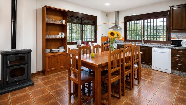 Una cocina con mesa, sillas, estufa y ventana con vistas.