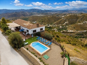 Uma casa com piscina, rodeada por um jardim e vista para o campo.
