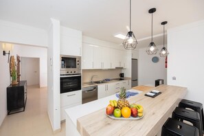 Eine moderne Küche mit weißen Schränken, Edelstahlgeräten und einer Holztheke mit Obst.