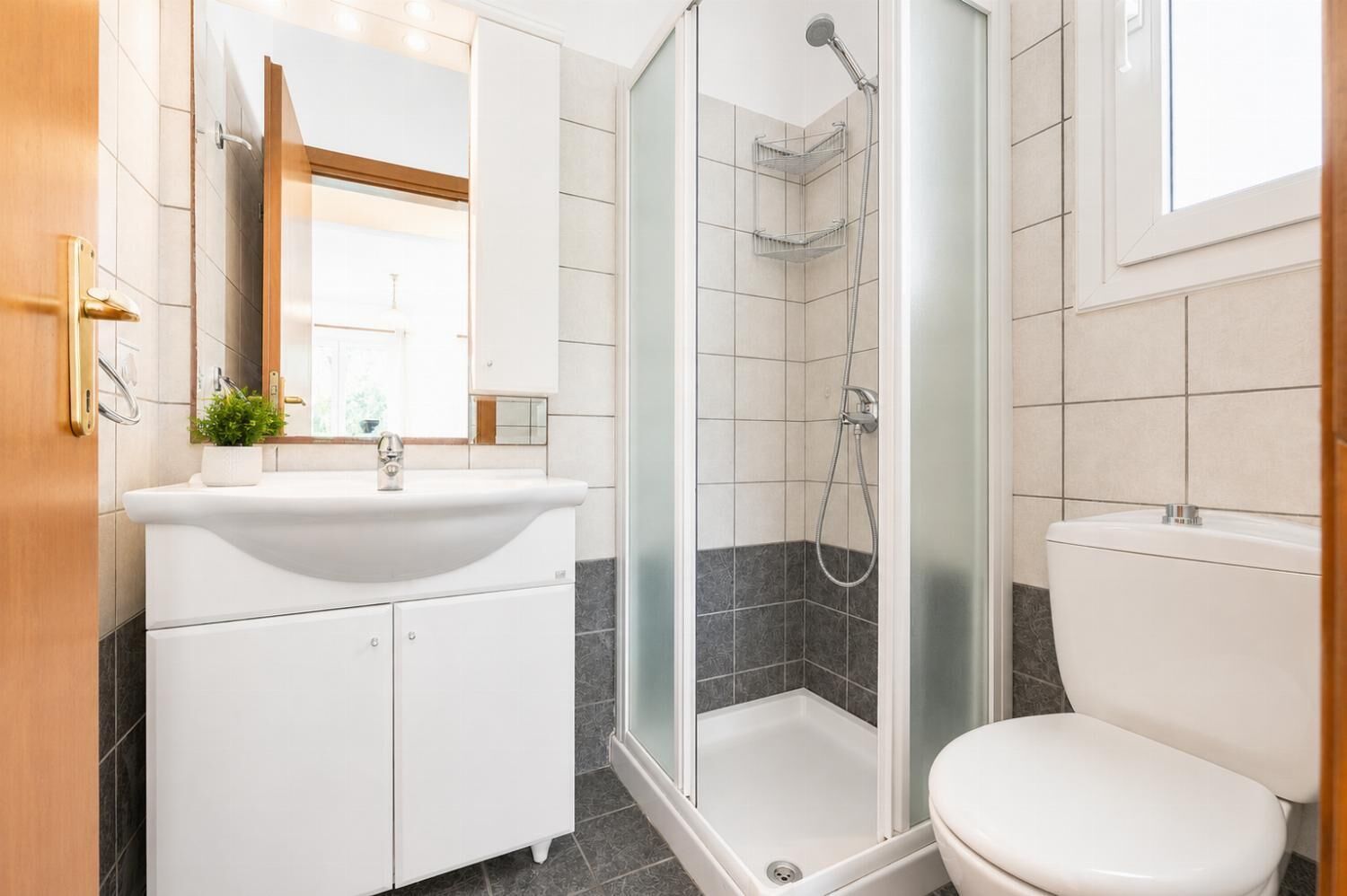A modern bathroom with a glass-enclosed shower, a white sink, and a toilet.