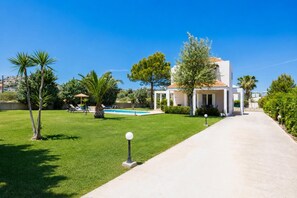 A modern house with a swimming pool, a well-maintained lawn, and a clear sky.