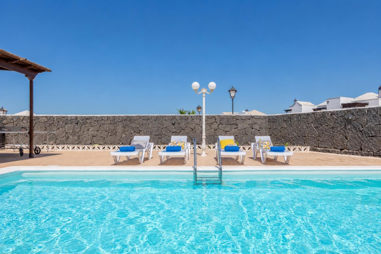 Une piscine avec des chaises longues et un mur en pierre.