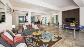 A spacious living area with a sofa, coffee table, and a ping pong table.