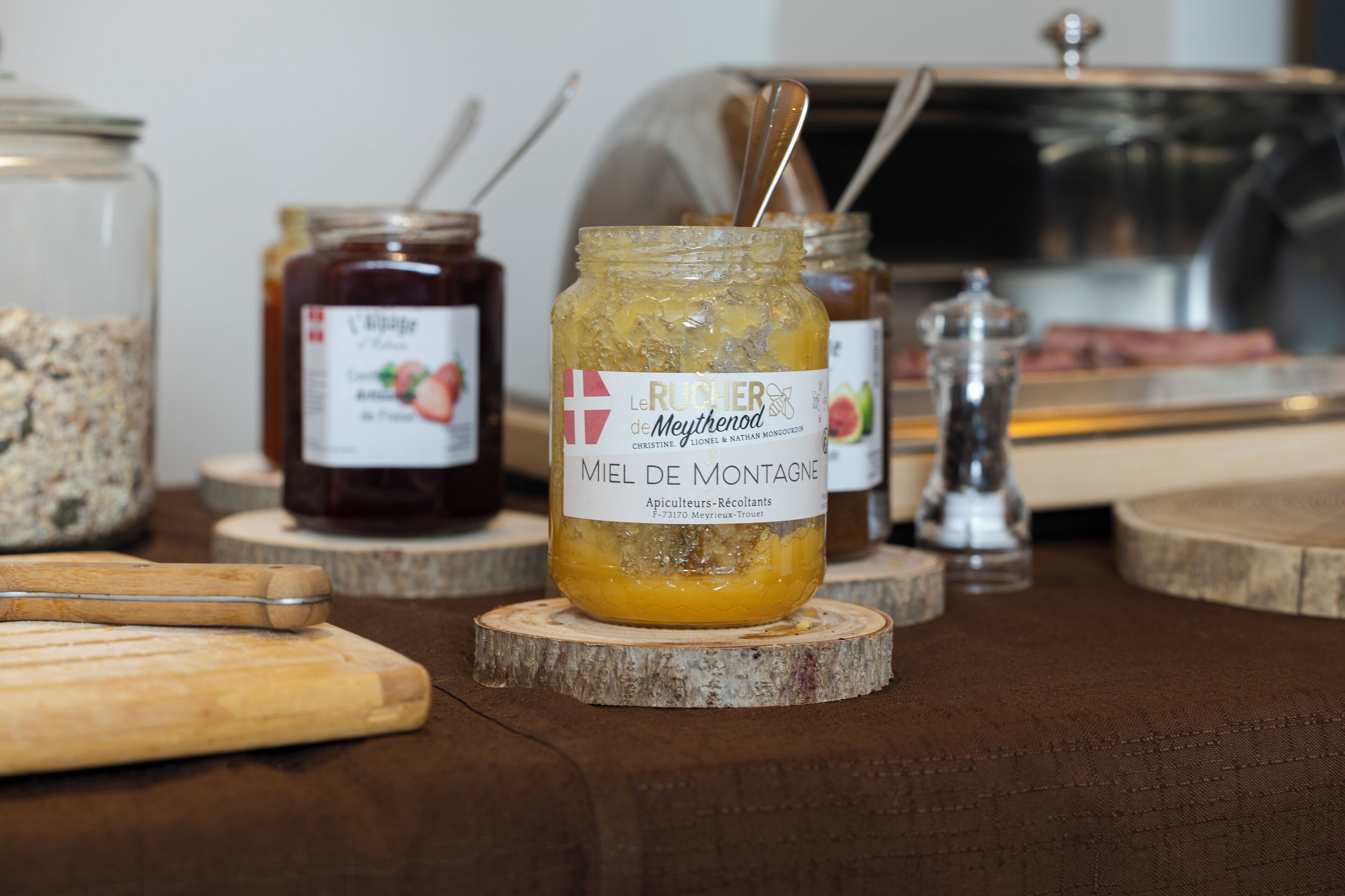 A wooden table with jars of preserves and a knife.
