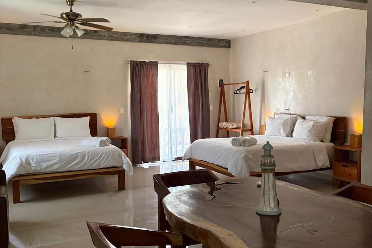 Une chambre d’hôtel avec deux lits, une table à manger et un ventilateur de plafond.
