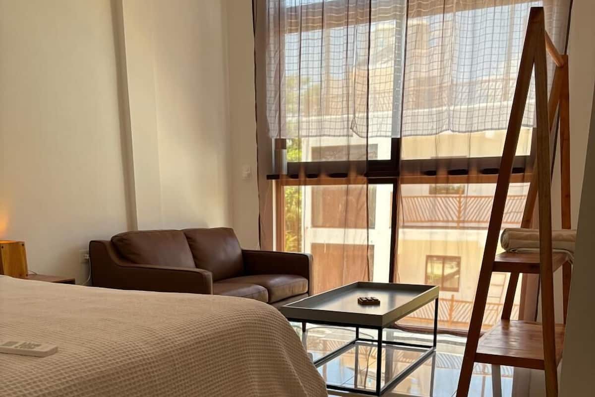 Une chambre moderne avec un lit, une petite table, un canapé et une échelle.