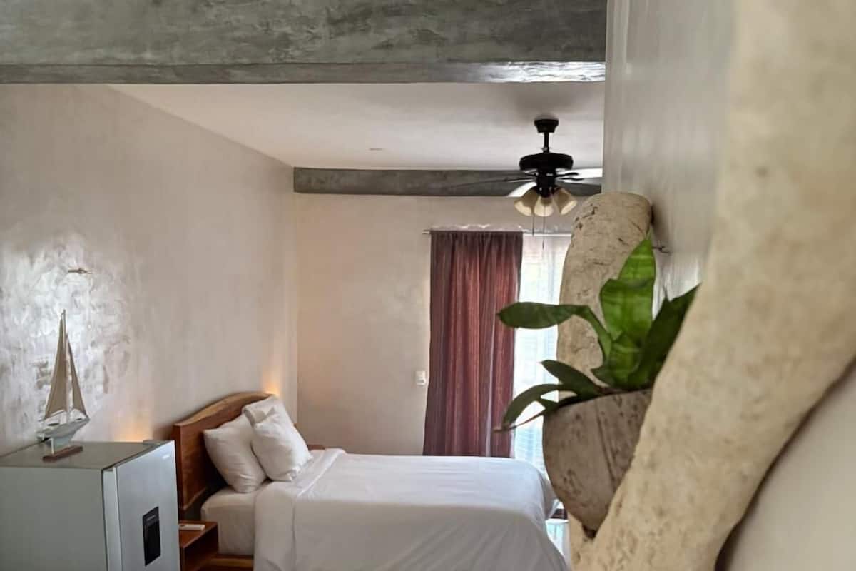 Une chambre à coucher avec un lit, un bureau et une plante.