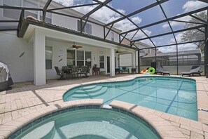 A covered outdoor swimming pool with a patio area, including seating and a small table.