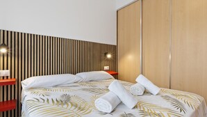 A modern hotel room with a bed, wooden panel wall, and a nightstand with a lamp. - Sol Montemar 10 - Terrace, Swimming Pool, Parking, 2 bedrooms (Torremolinos)