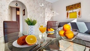 A modern living room with a glass dining table, two leather chairs, a sofa, and a decorative plant. - Sol Montemar 10 - Terrace, Swimming Pool, Parking, 2 bedrooms (Torremolinos)