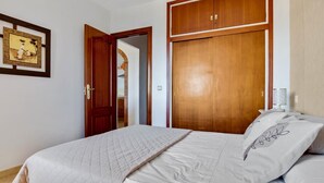 A bedroom with a bed, a wardrobe, a door, and a framed picture on the wall. - Santa Amalia 51 - Terrace, Swimming Pool, Parking, Sea Views (Torremolinos)