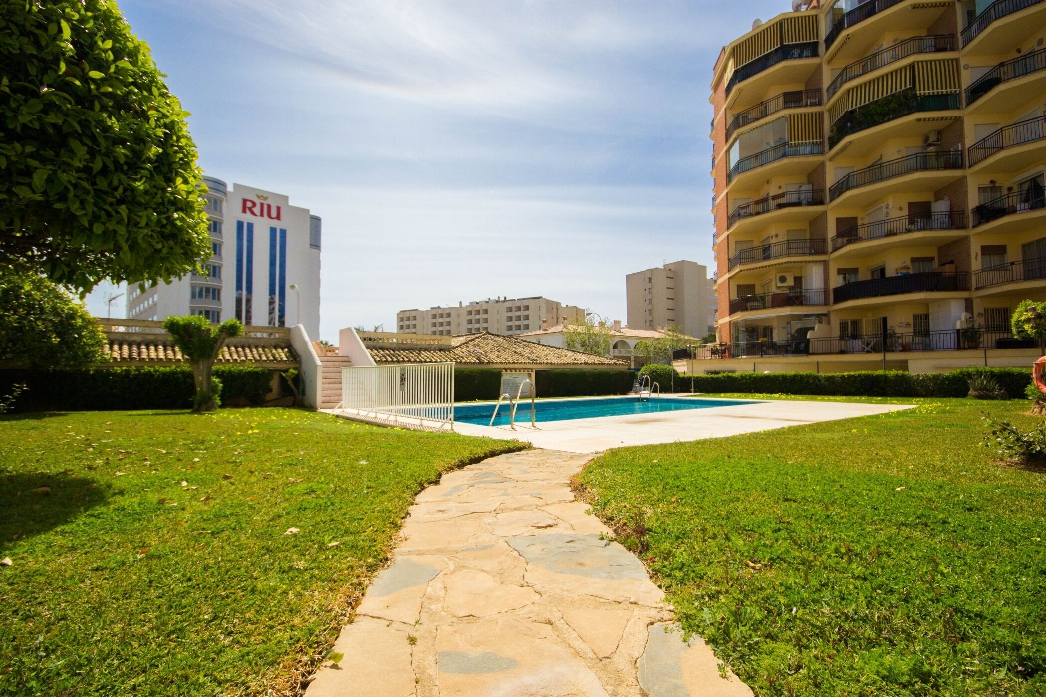 A courtyard with a swimming pool, stone pathway, and a building with 'RJU' signage.
