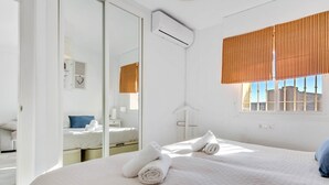 A hotel room with two beds, a large mirror, a window with striped curtains, and a view of buildings outside. - Erisa 1, 68 - Terrace, Swimming Pool, Parking, Second line of beach. 1 bedroom (Torremolinos)