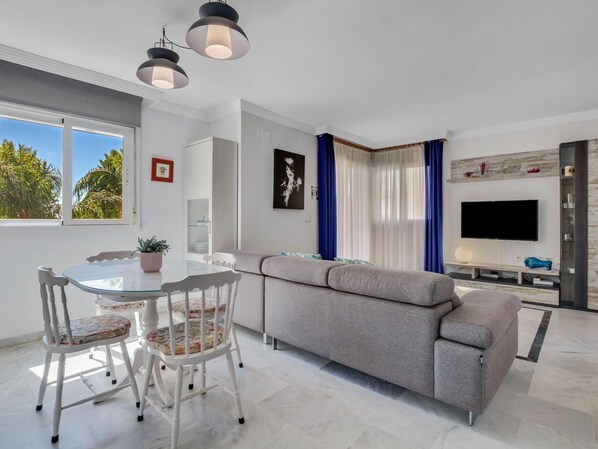 Relax in a stylish living space with a dining area, sofa, flat-screen TV, and large window offering a view of the outdoors.