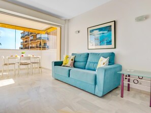 A modern living room with a blue sofa, a dining table with chairs, a glass coffee table, and a framed picture on the wall. - Erisa 1, 59 - Terrace, Swimming Pool, Parking, Second line of beach. Sea Views (Torremolinos)